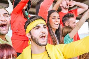 Happy football supporter fans watching world soccer game - Young group of excited friends having fun exulting at stadium - Youth, sport and celebration score concept photo