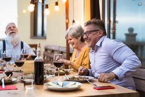 Happy senior friends having fun dining together on house patio - Elderly lifestyle people and food concept photo