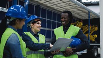 Team of multiracial engineers working in robotic factory monitoring the project on laptop - Tech industry concept photo