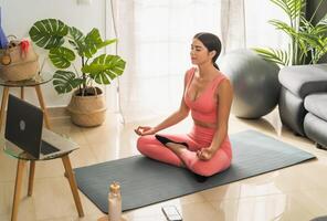 latín joven mujer haciendo yoga virtual aptitud clase con ordenador portátil a hogar - e-learning y personas bienestar estilo de vida concepto foto