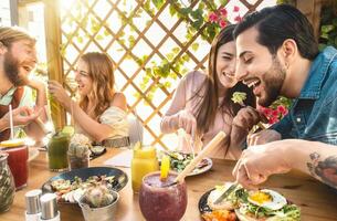 contento amigos almorzando con sano comida en bar café desayuno tardío - joven personas teniendo comida comiendo y Bebiendo batidos Fresco frutas en rústico restaurante - salud dieta estilo de vida concepto foto