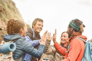 grupo de amigos apilado manos mientras haciendo trekking excursión en montaña - joven turistas teniendo divertido explorador el salvaje naturaleza - excursionista, equipo, caminata y viaje personas concepto foto