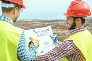 trabajadores ingenieros leyendo y hablando acerca de el nuevo renovable energía proyecto - dos constructores que se discute cómo a construir molino y paneles solar - construcción, ambiente, ahorro naturaleza concepto foto