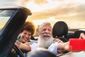 contento mayor Pareja teniendo divertido en nuevo convertible coche viaje tomando selfie con móvil teléfono inteligente - viaje personas estilo de vida concepto foto