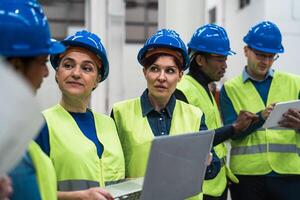 equipo de diverso ingenieros trabajando en robótico fábrica - tecnología industrial concepto foto