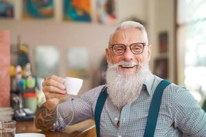 Happy smiling senior man drinking coffee in bar restaurant - Hipster trendy older male portrait - Lifestyle people concept photo