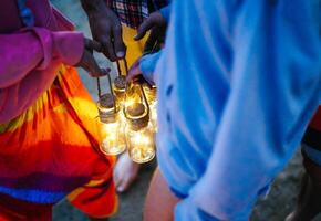 Hipster friends having fun while camping with tent on the beach - Young people holding bright lanterns in campsite on summer - Concept of friendship, travel, vacation and youth lifestyle photo