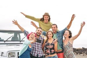 grupo joven amigos tomando selfie con móvil teléfonos inteligentes durante la carretera viaje - contento viaje personas teniendo divertido en vacaciones - amistad estilo de vida y juventud cultura concepto foto