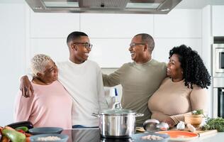 Happy black family having fun cooking together in modern kitchen - Food and parents unity concept photo