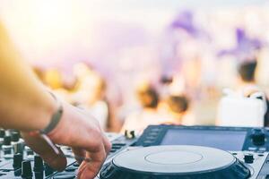 Close up of DJ's hand playing music at turntable on a beach party festival - Portrait of DJ mixer audio in a beach club above the crowd dacing and having fun - Party, summer, music and people concept photo