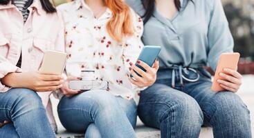 Happy trendy friends using mobile phone outdoor - Young millennial people addicted to new smartphone technologies - Concept of youth culture lifestyle and addiction people with technology photo
