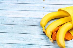 yellow bananas lying in a yellow bag on a blue wooden background photo