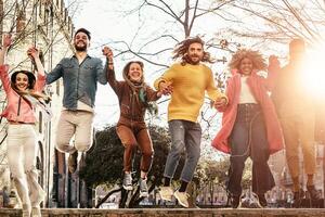 grupo de contento amigos saltando al aire libre - milenario joven personas teniendo divertido bailando y celebrando a puesta de sol fuera de - amistad, urbano vida y juventud estilo de vida concepto foto