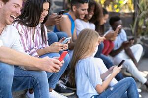 Young multiracial group of friends using mobile smartphone sitting on stairs - Youth millennial lifestyle concept photo