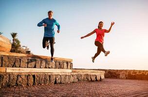 ajuste Pareja haciendo rutina de ejercicio corriendo sesión a puesta de sol al aire libre - deportivo joven personas trotar siguiente el playa - sano estilo de vida y deporte concepto foto