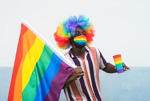 negro gay hombre teniendo divertido celebrando gay orgullo festival vistiendo cara protector máscara para prevenir corona virus untado foto