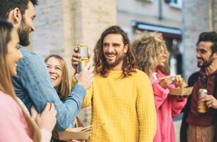 Happy friends eating street food and drinking beers outdoor - Group trendy people having fast meal together - Youth culture and city lifestyle concept photo