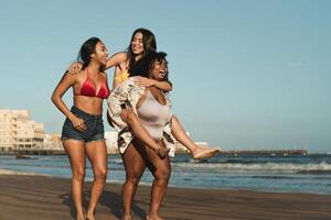 Happy multiracial girls with different size having fun on the beach during summer holidays photo