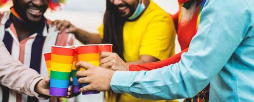 Happy multiracial people cheering and drinking cocktails in gay pride festival event during corona virus pandemic photo