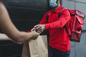 Rider man delivering meal to customers with electric scooter while wearing face mask during corona virus outbreak - Ecological fast delivery food concept photo