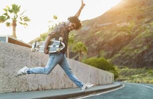 contento afro hombre teniendo divertido bailando mientras escuchando a música con inalámbrico auriculares durante verano hora foto