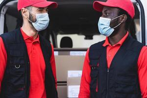 Young delivery men working while wearing face mask to avoid corona virus spread - People working with fast deliver during corona virus outbreak photo