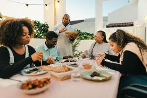 Happy African family dining together on house patio - Family Gatherings concept photo