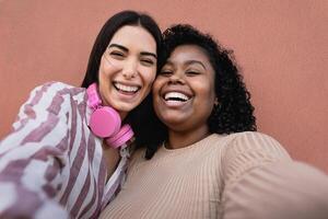 Happy Hispanic friends having fun taking selfie with mobile smartphone outdoor - Technology and social media concept photo