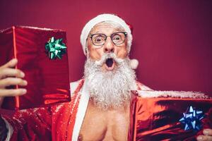 contento ajuste Papa Noel claus riendo y dando Navidad regalos - de moda barba tatuaje hipster mayor vistiendo Navidad ropa y participación regalos - celebracion y Días festivos concepto foto