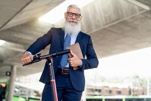 Senior business man going to work with electric scooter around city center photo