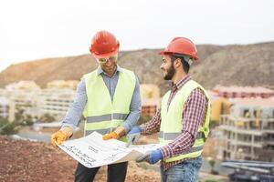 Workers engineers discussing about the new building area - Young builders reading the project in the construction site - Teamwork, carpentry, engineering concept photo