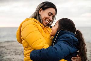 contento latín madre con hija disfrutando juntos durante un invierno día - familia y amor concepto foto