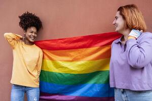 Happy gay couple celebrating pride holding rainbow flag outdoor - Lgbt and love concept photo