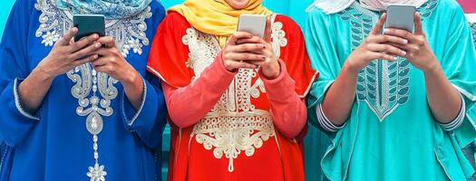 joven musulmán personas utilizando su móvil inteligente Los telefonos en el Universidad - árabe muchachas fanático a nuevo tecnología aplicación Teléfono móvil para social medios de comunicación - milenario, religión, Generacion z y tecnología concepto foto