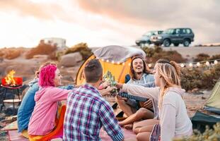 Happy friends toasting beers at barbecue camping party - Group young hipster people having fun dining and drinking together in campsite - Travel vacation lifestyle and youth culture concept photo