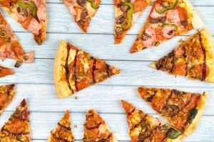 Lots of delicious triangular pizza slices on a blue wooden background photo