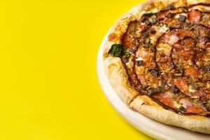 Delicious large pizza with bacon and spinach on a yellow background photo