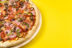 Delicious large pizza with veal and mushrooms on a yellow background photo