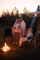 The family is relaxing together by the campfire near their mobile home. Evening family vacation photo