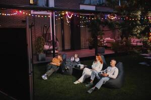 family mother, father and children watch a projector, movies with popcorn in the evening in the courtyard photo
