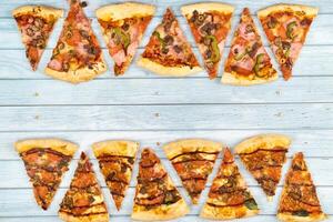 Lots of delicious triangular pizza slices on a blue wooden background photo