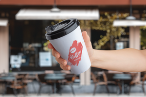 logo Bosquejo en un papel para llevar taza retenida en mano en frente de un café tienda psd