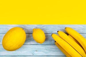 An assortment of yellow fruits lies on a blue wooden background and a yellow background photo