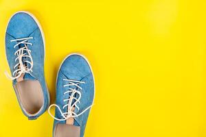 Blue shoes stand on an isolated yellow background photo