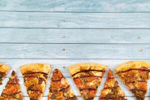 Lots of delicious triangular pizza slices on a blue wooden background photo