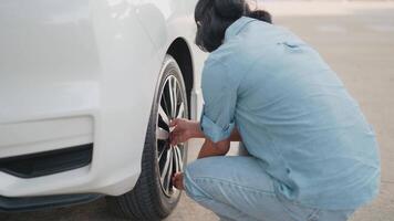 donna controlli un' piatto pneumatico foratura mentre in attesa per un' pneumatico e auto servizio tecnico per chiamata per aiuto. video