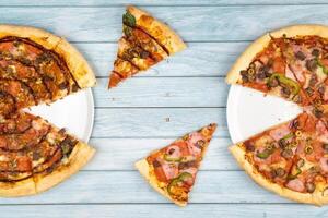 Two different delicious big pizzas on a blue wooden background photo