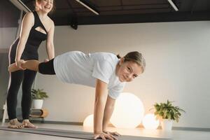 Mom and teenage daughter do gymnastics together in the fitness room. A woman and a girl train in the gym photo