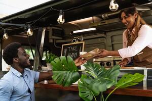 joven africano hombre comprando comida desde comida camión - moderno negocio y tomar lejos concepto foto