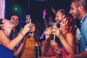 grupo de amigos bailando y Bebiendo champán a Club nocturno fiesta - contento joven personas teniendo divertido celebrando juntos en disco club - entretenimiento, la vida nocturna y juventud estilo de vida foto